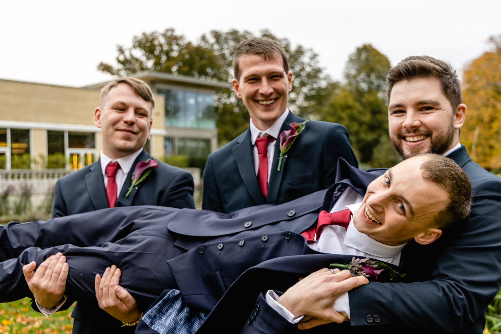 Groomsmen hold the laughing groom aloft on the lawns outside Sopwell House