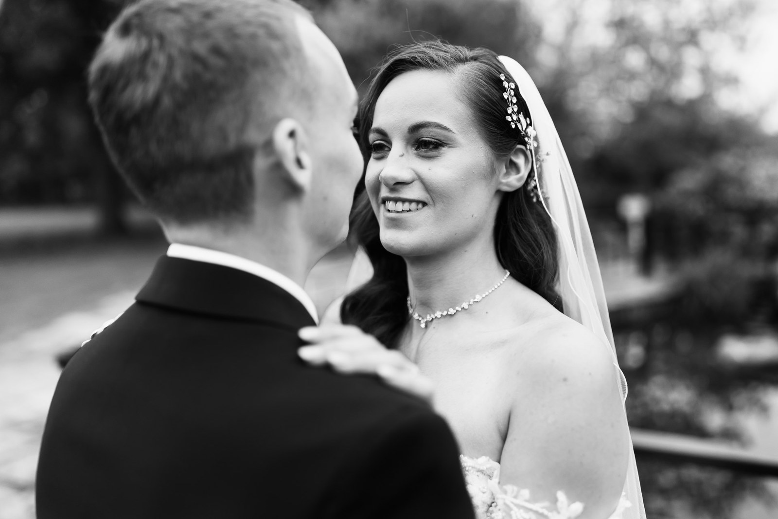Black and white of the bride resting a hand on the groom's shoulder