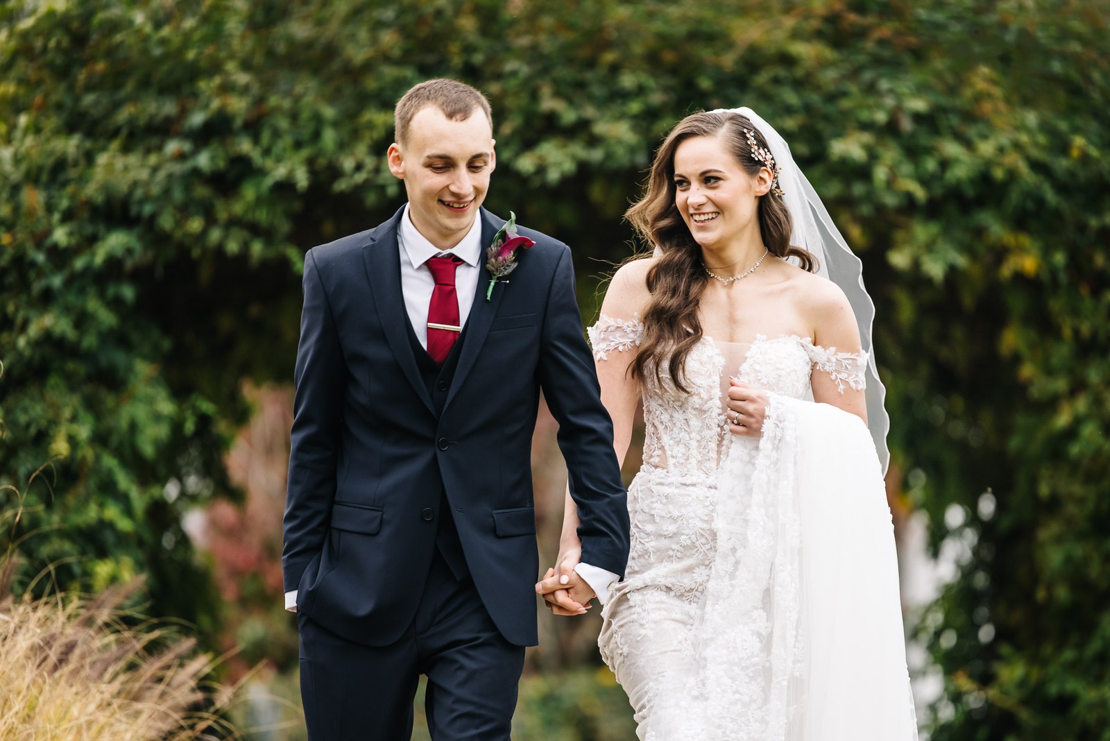 The newlyweds walk hand in hand through the autumn gardens at Sopwell House