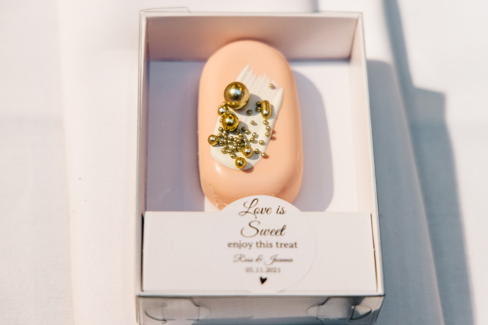 A 'Love is Sweet' wedding favour box holding a small iced treat