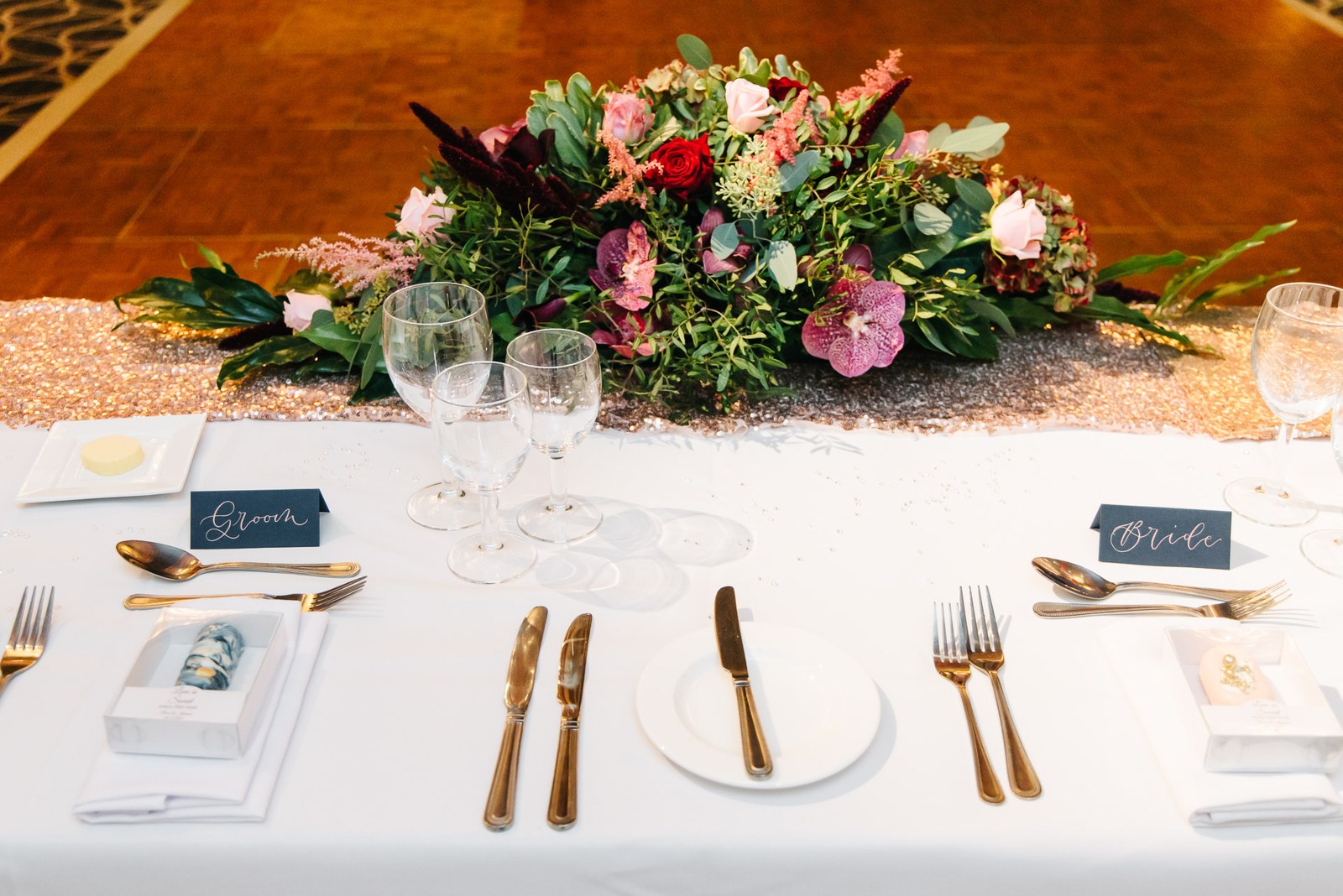 Top-table floral centrepiece with gold cutlery and calligraphed name cards