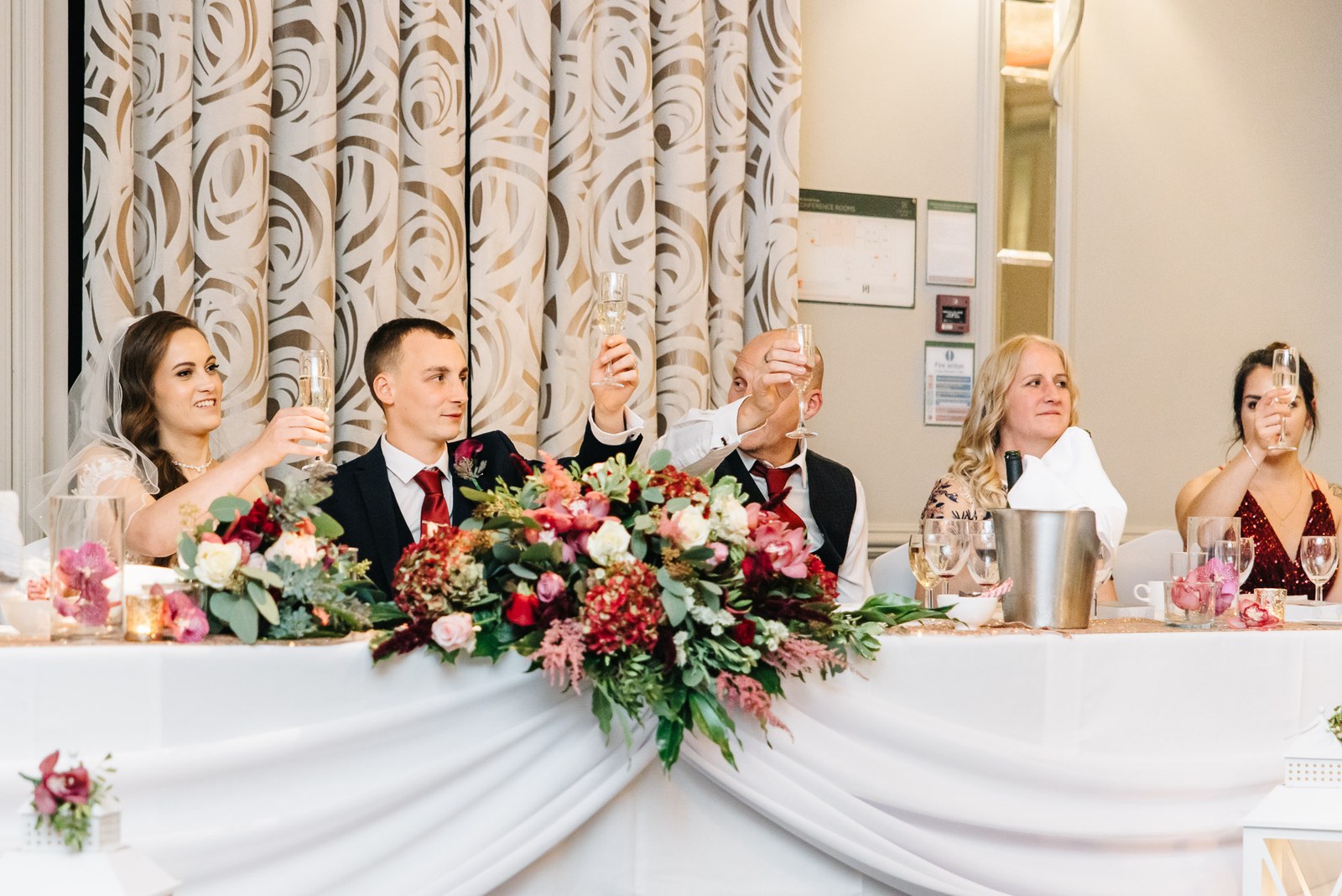 The wedding party raise a toast along the flower-dressed top table