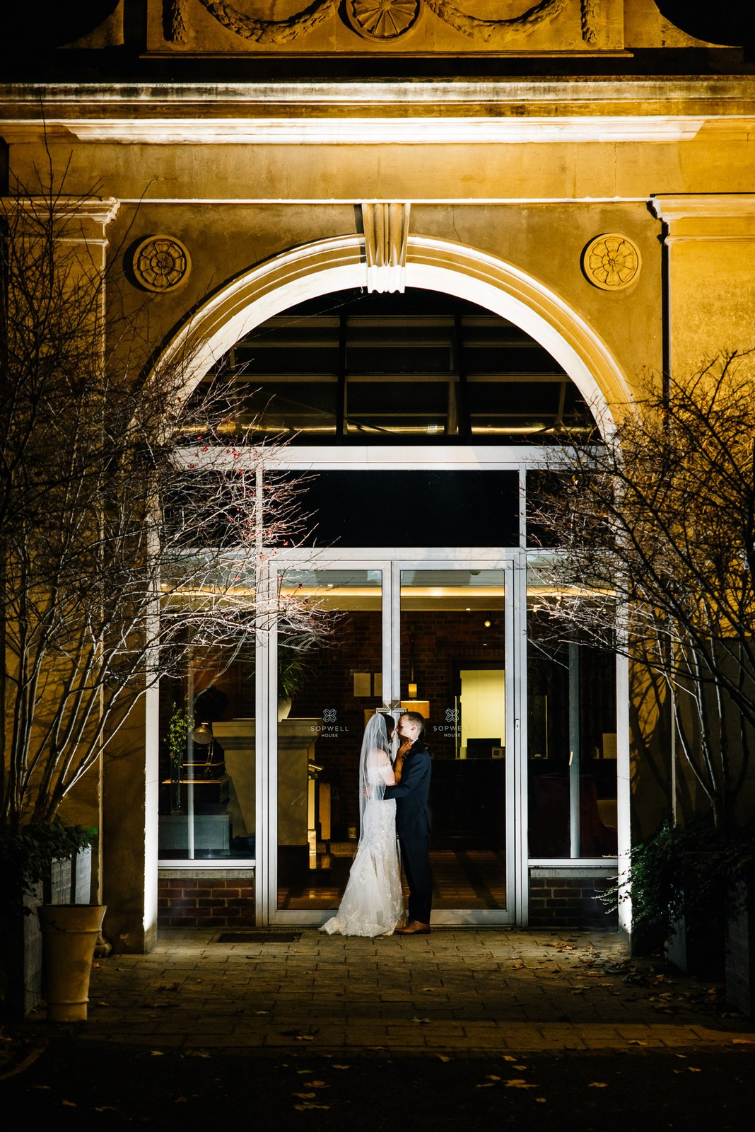 The couple silhouetted in the lit arched entrance of Sopwell House at night