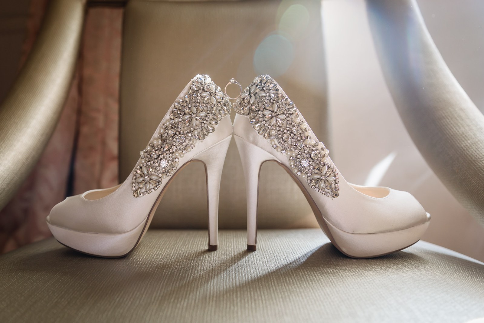 Bridal heels with sparkling diamante detail catching the light on a chair