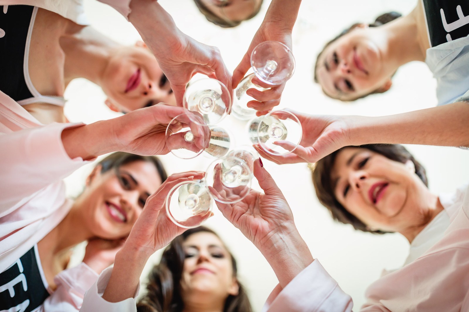 View from below as the bridal party clink their champagne glasses overhead
