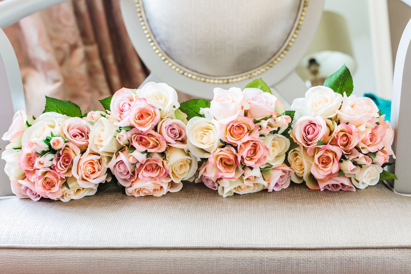 A line of blush and cream roses laid out on an upholstered seat