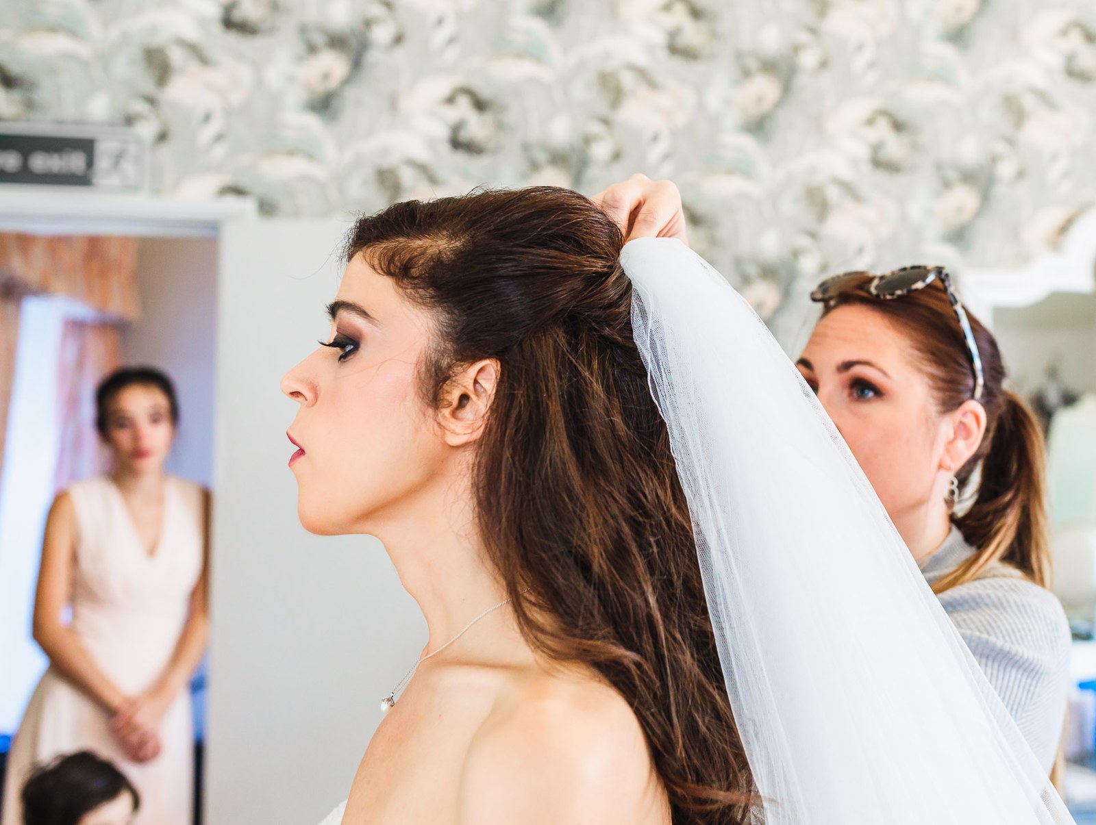 Bride in profile settling her veil during the morning preparations