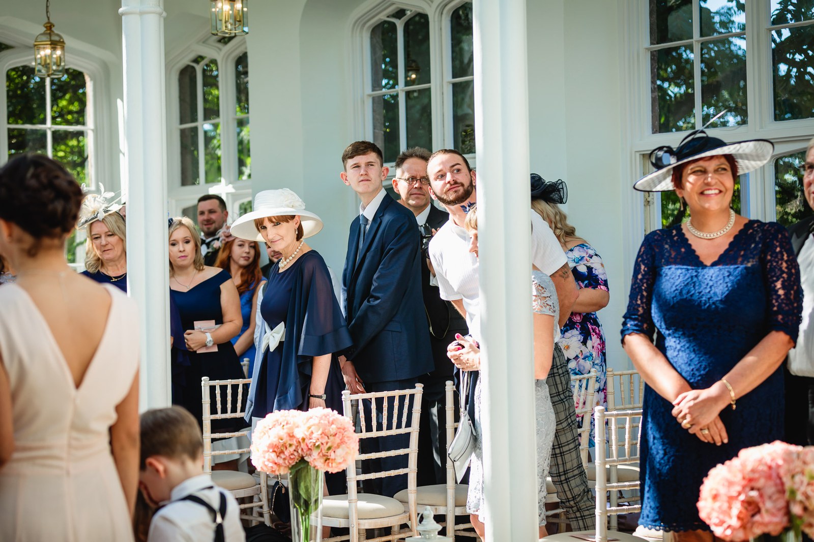 Guests rise in the bright St Audries Park orangery as the bride arrives