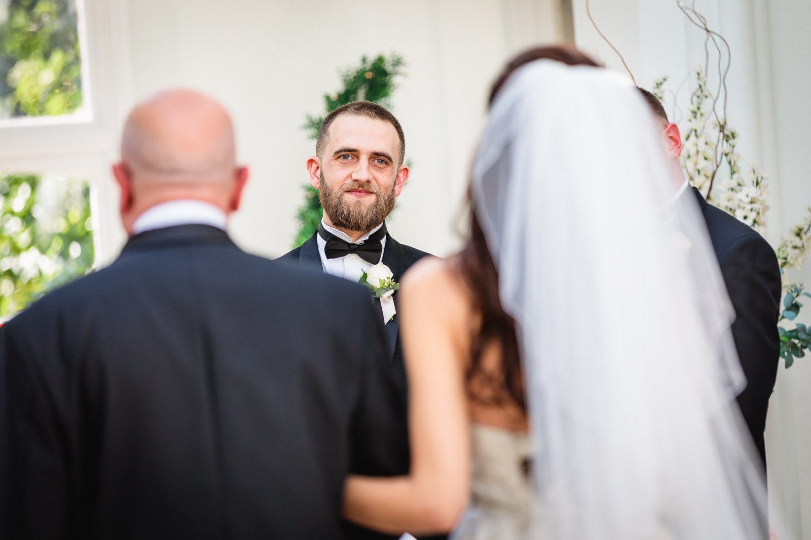 The groom smiles as the bride reaches him at the front of the ceremony