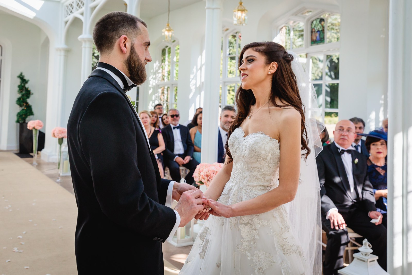 The couple hold hands facing each other in the light-filled orangery
