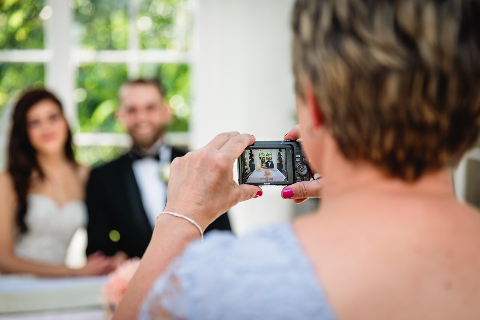 A guest captures the newlyweds on her camera at the front of the ceremony