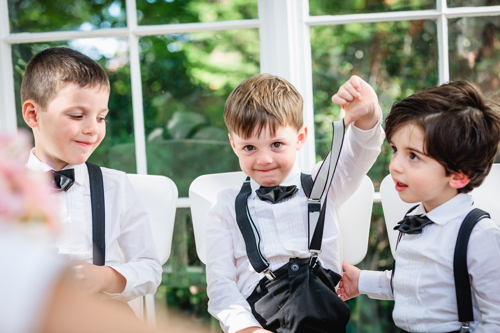 Three page boys in braces and bow ties, one punching the air