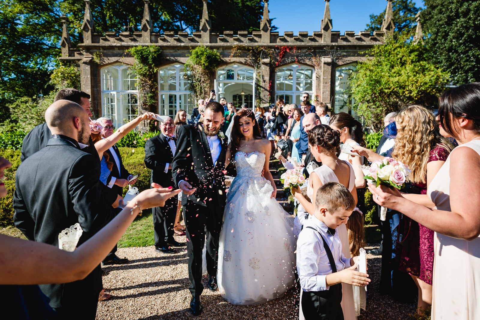 Guests shower the couple with confetti before the ivy-clad St Audries Park wall