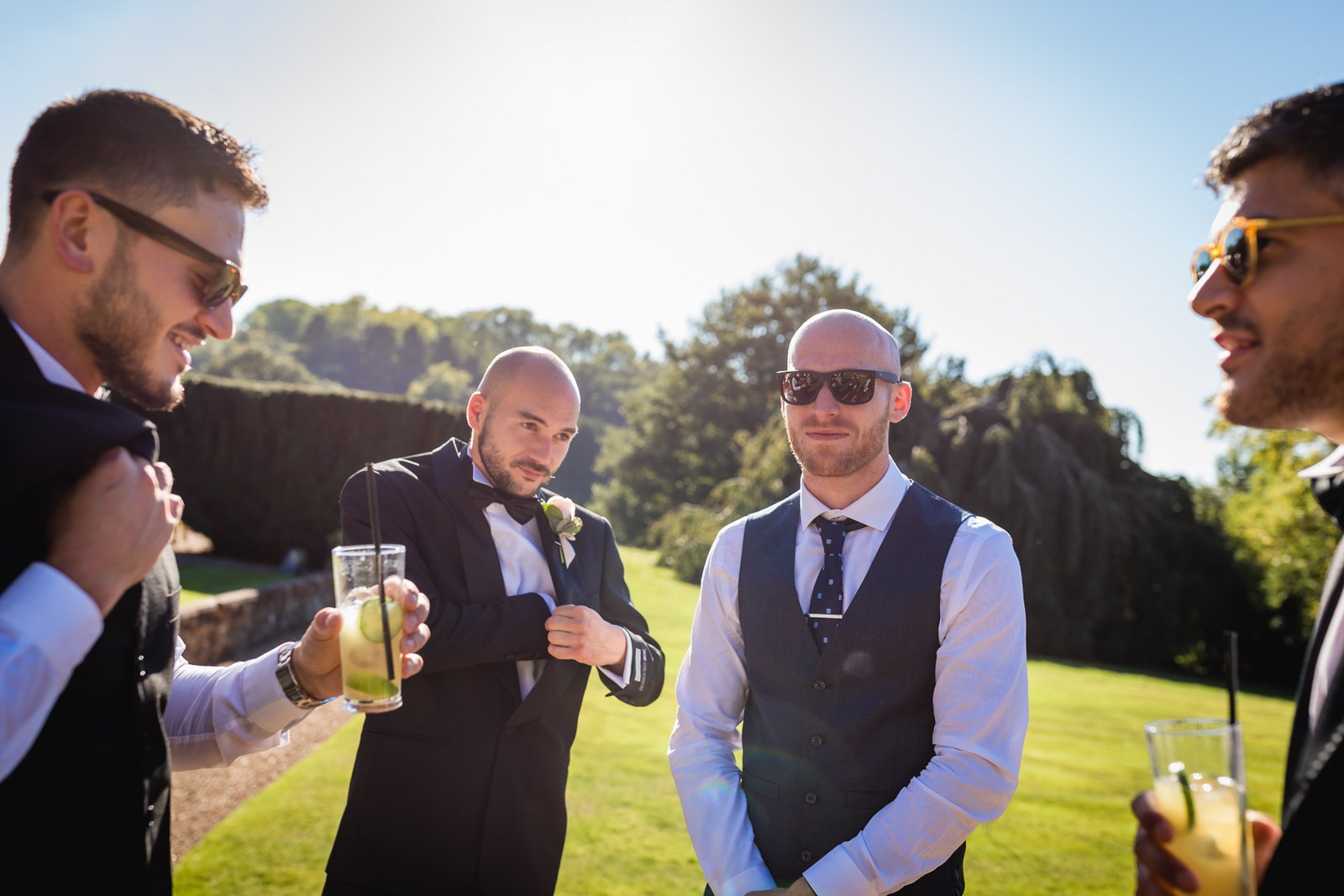 Male guests in sunglasses share a drink together in the sunshine