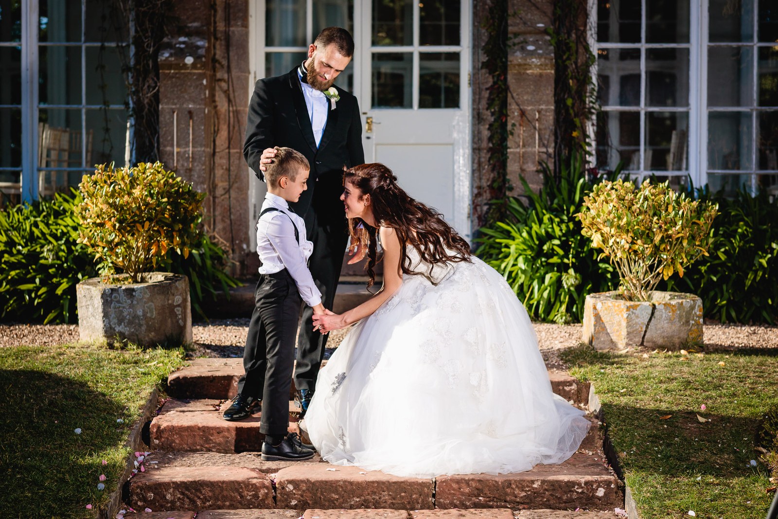 The couple pause on the red stone steps with a page boy between them