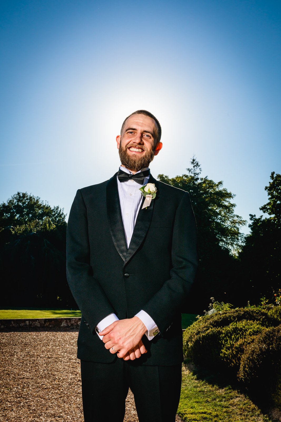 Portrait of the groom in black tie against a clear blue sky