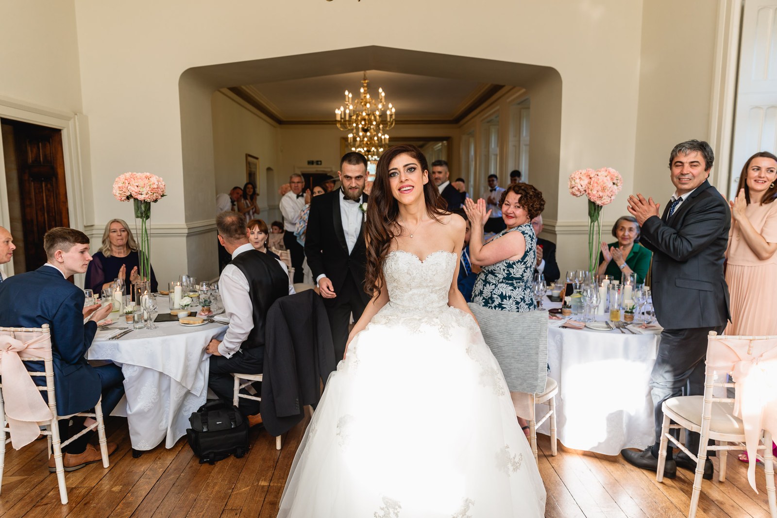 Bride enters the candlelit reception to applause from seated guests
