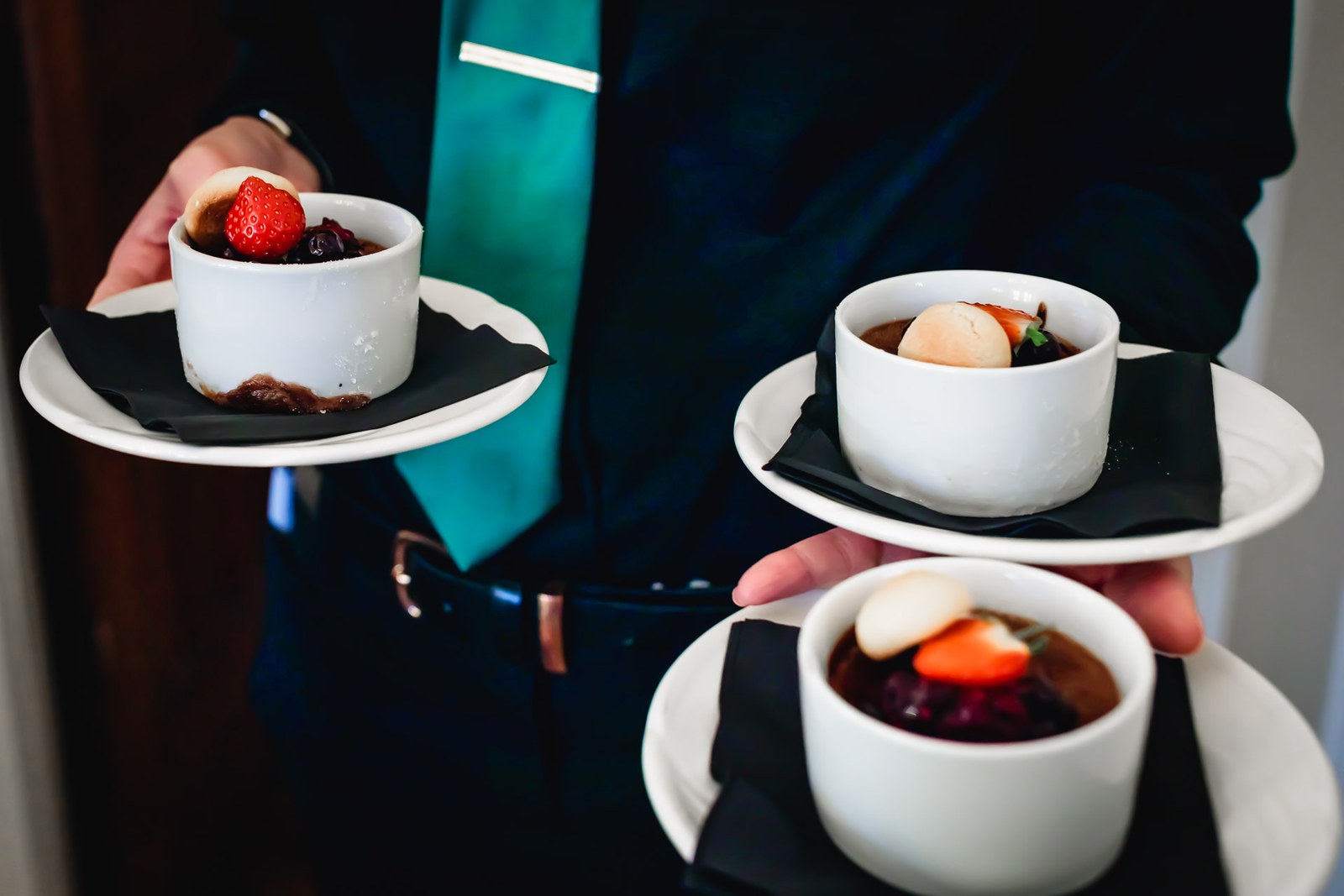 Individual berry desserts served on slate plates by waiting staff