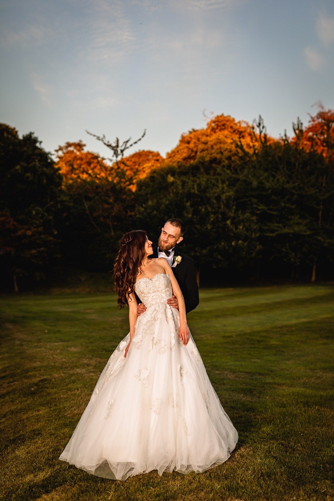 The newlyweds hold each other at dusk on the manor's parkland