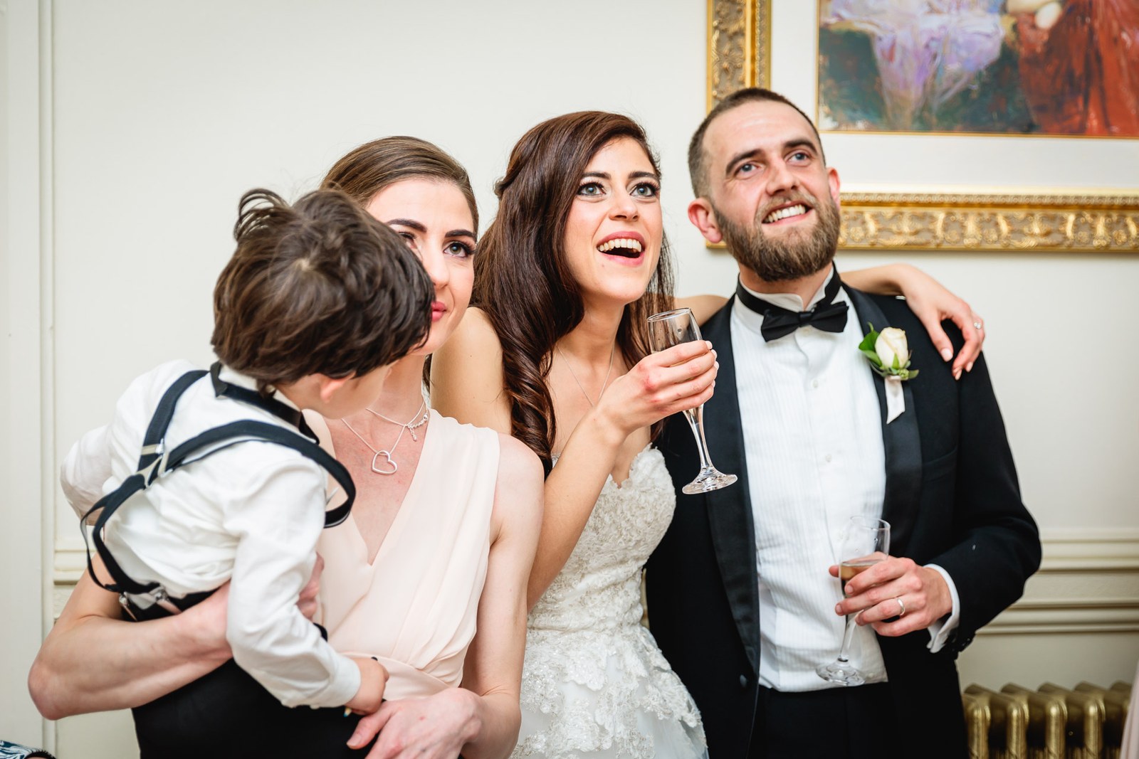 Bride and groom laugh with guests, champagne in hand