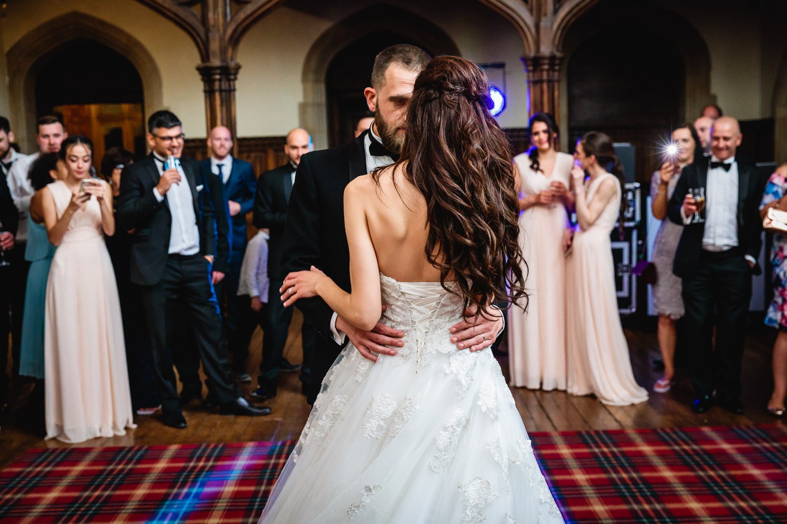 Bride and groom share their first dance as guests watch in the hall