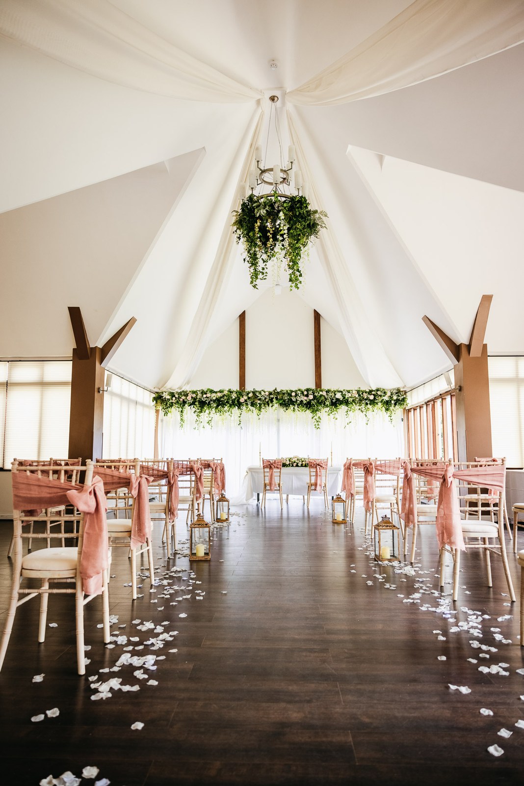 Steventon House Hotel's ceremony room draped in white, with pink-sashed chairs and a petal-strewn aisle