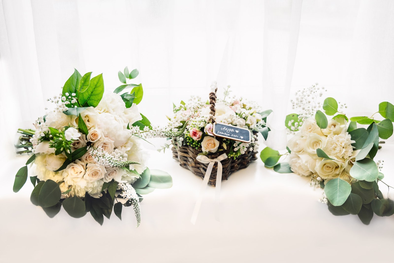The bride's bouquet, a smaller posy and a flower basket arranged on a bed