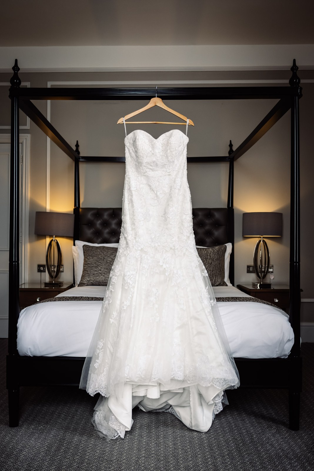 Strapless lace wedding dress hanging on a four-poster bed in a Steventon House Hotel bedroom