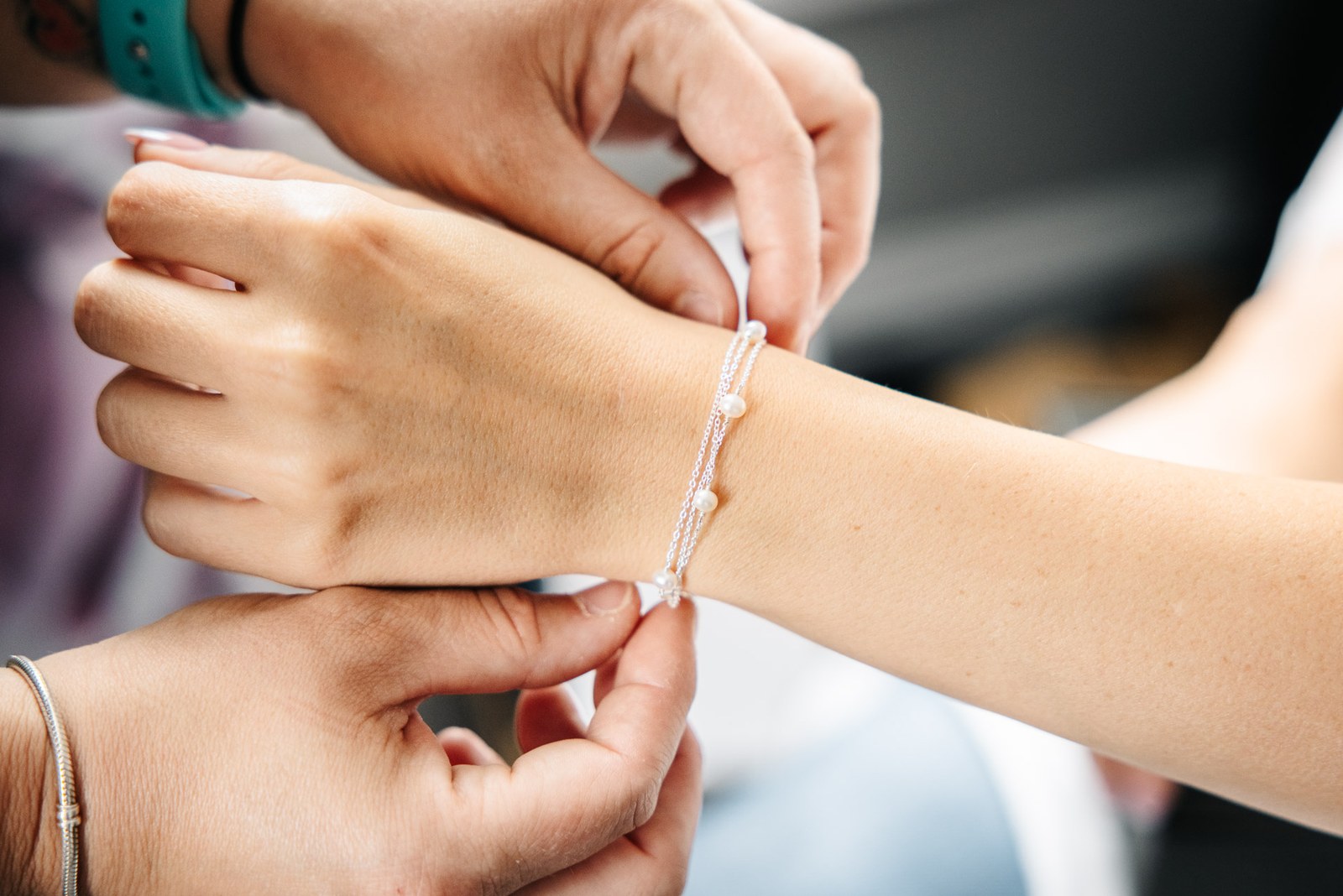 A delicate bracelet being fastened around the bride's wrist