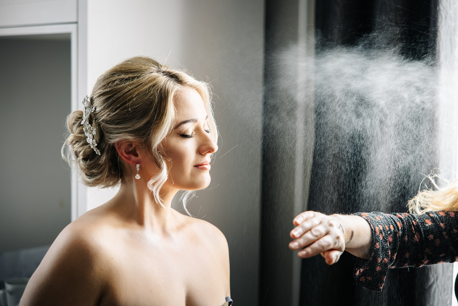 Hairspray setting the bride's finished updo before the veil goes on