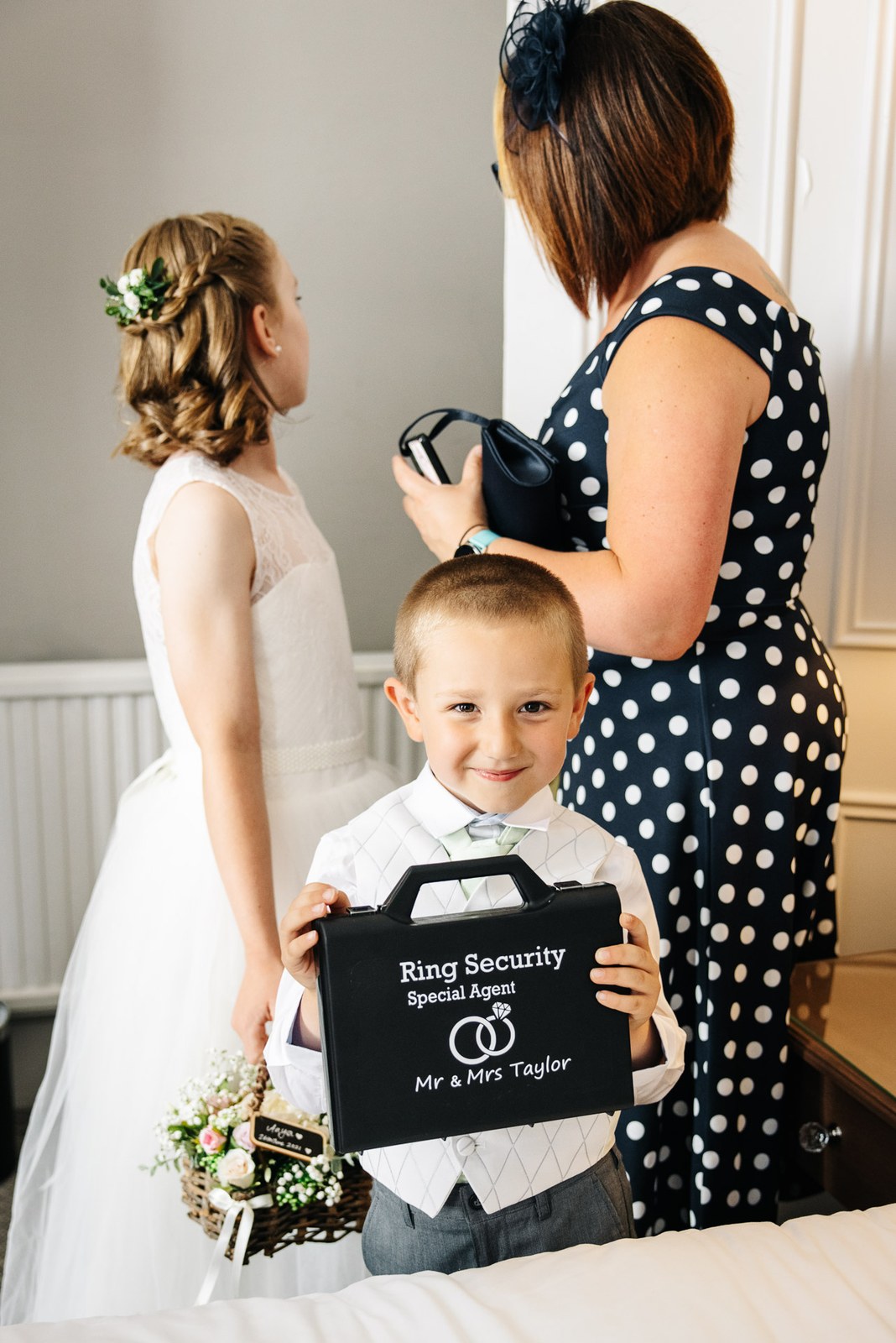 A young page boy holding a 'ring security' briefcase beside a flower girl