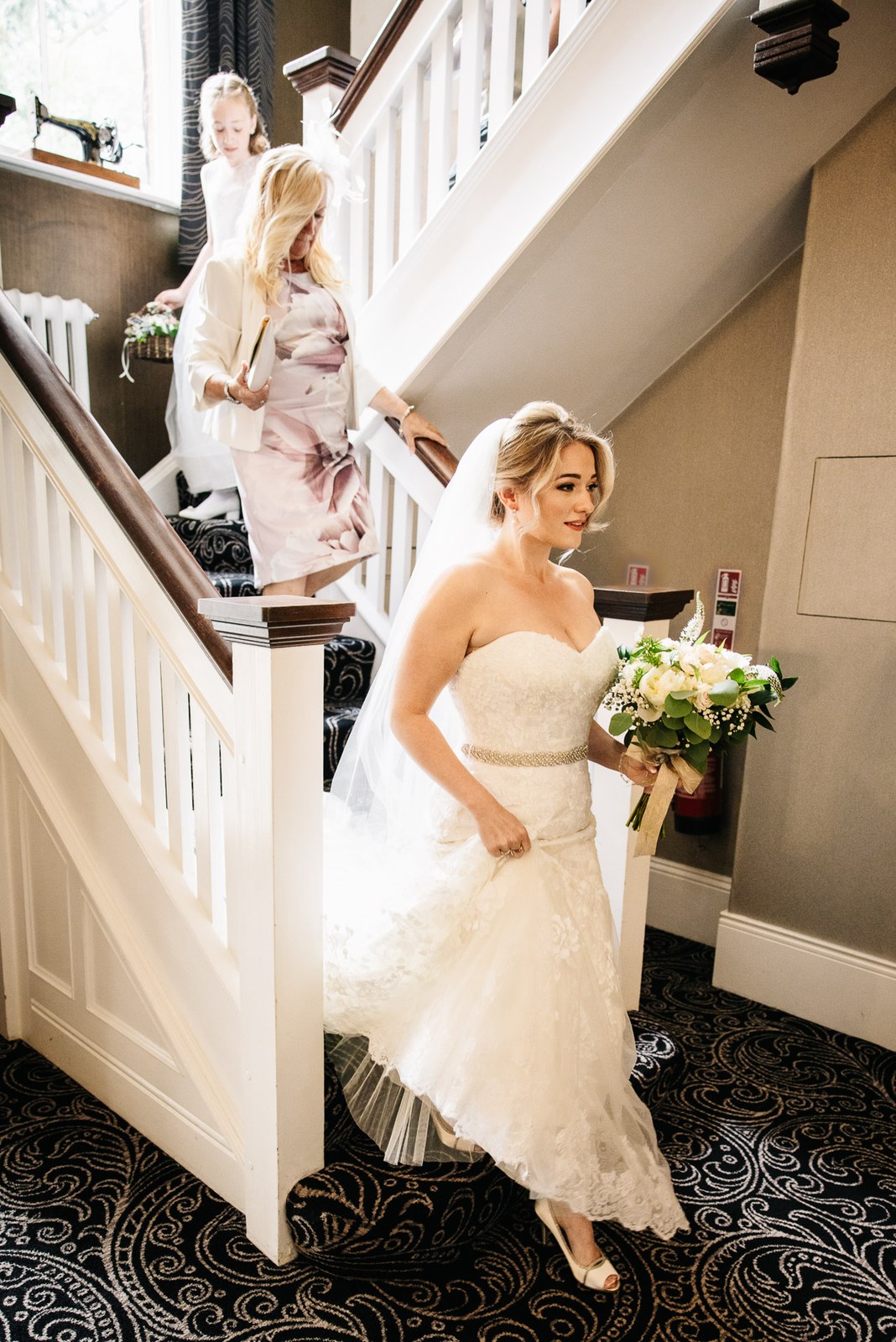 The bride on the staircase with a flower girl on the landing above