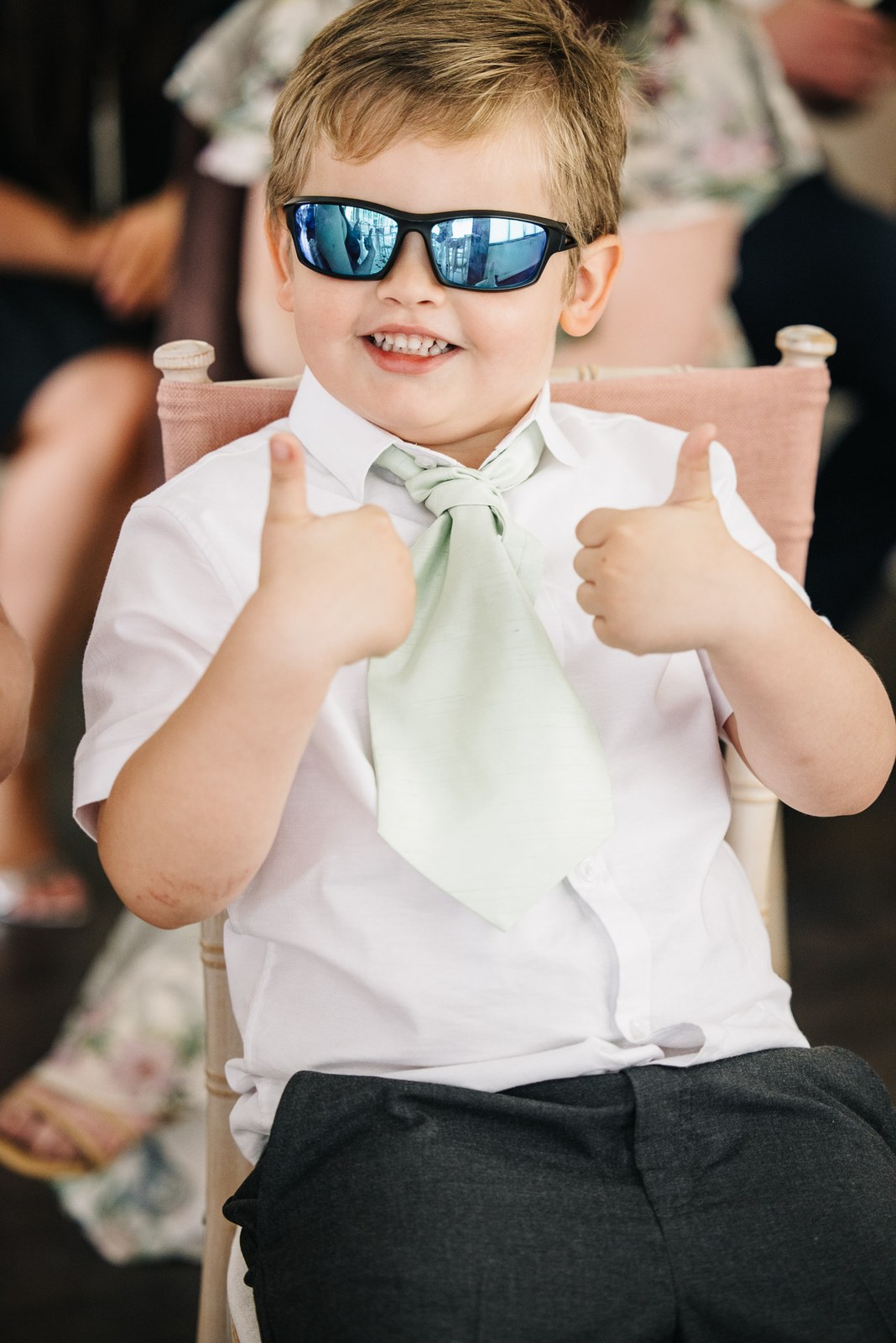 A page boy in sunglasses grinning and giving two thumbs up