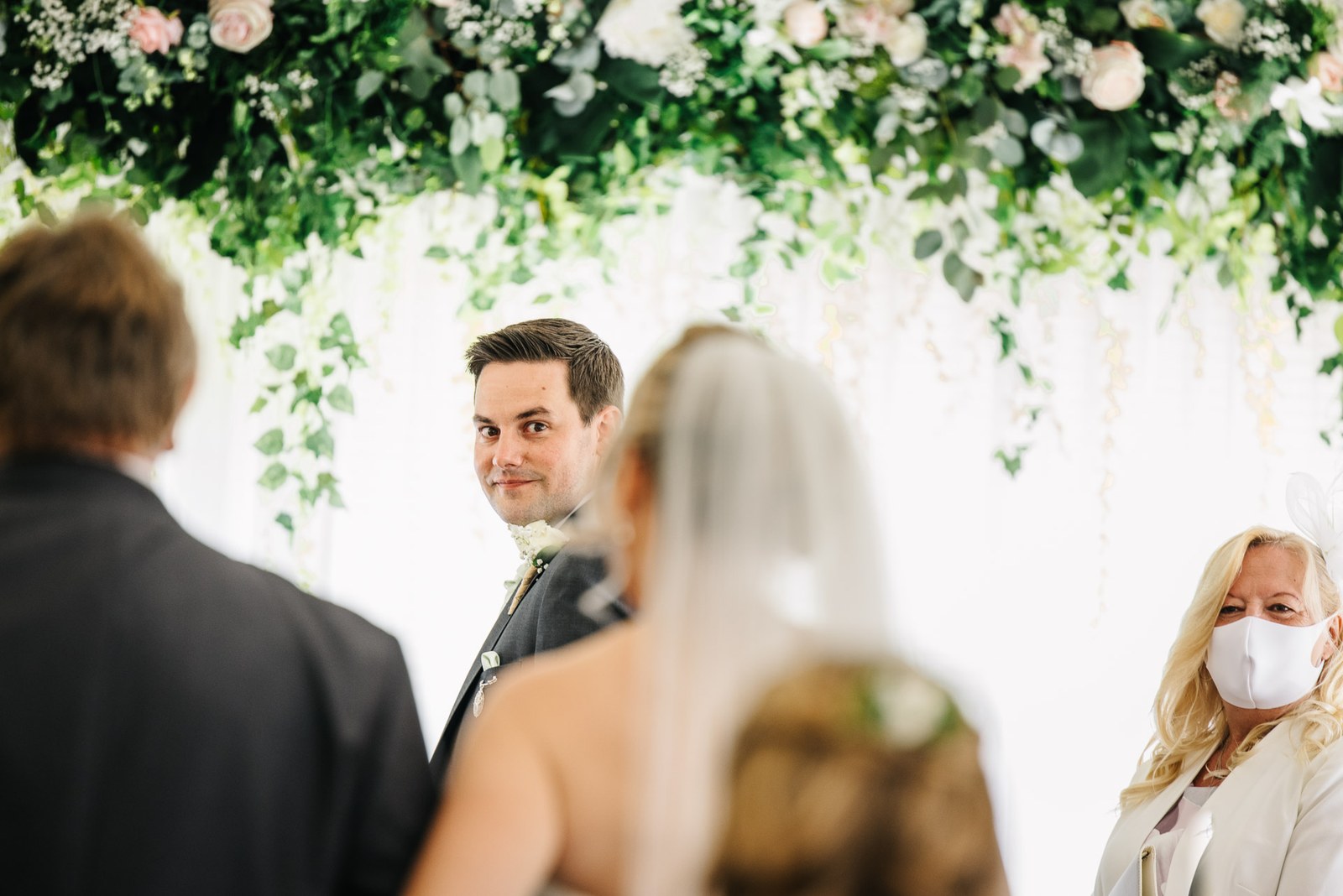 Bride and groom beneath a trailing greenery-and-flower ceremony arch