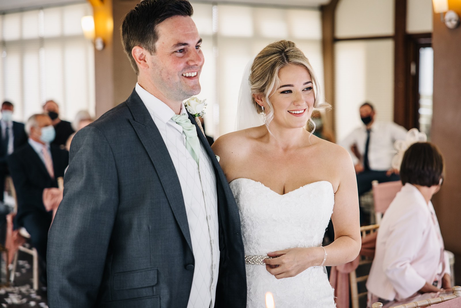 Bride and groom smiling together at the front of the ceremony room