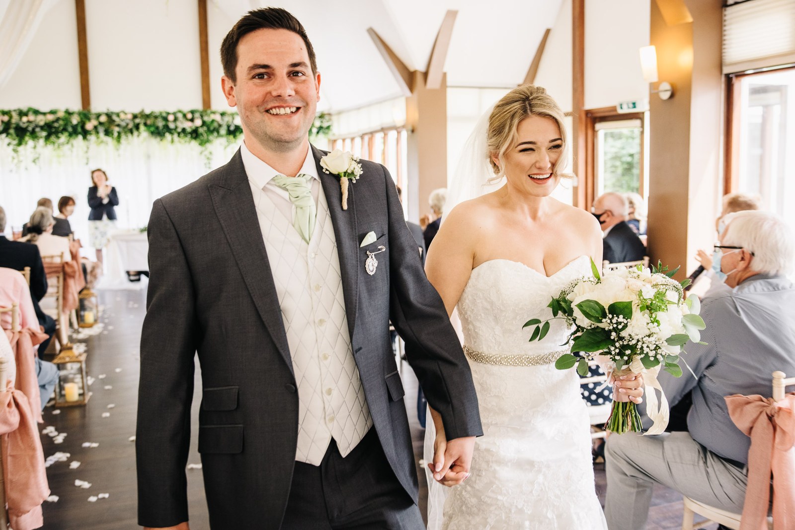 The newlyweds walking back down the aisle through their guests