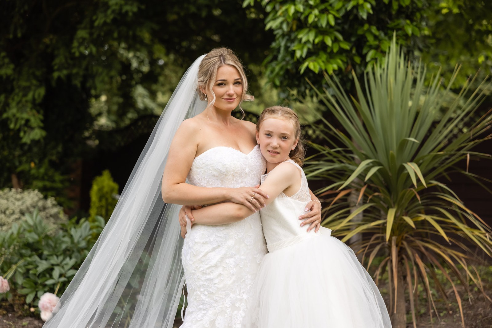 The bride hugging a flower girl among the garden greenery