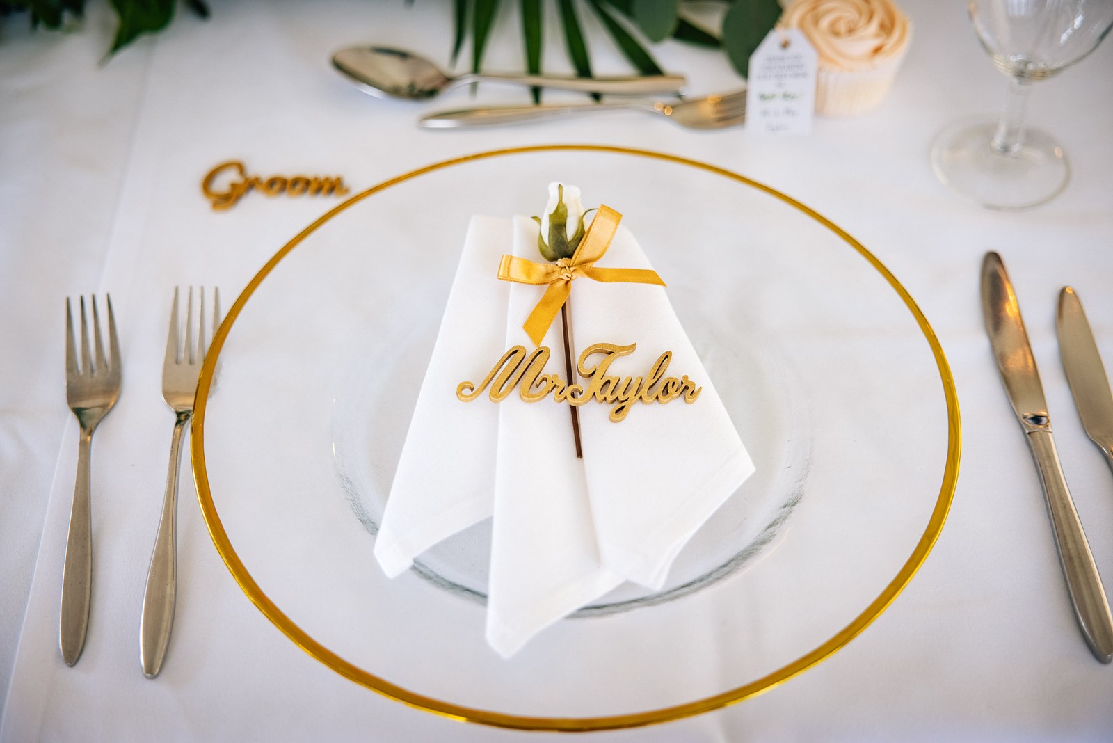A gold-rimmed place setting with a laser-cut 'Groom' name card