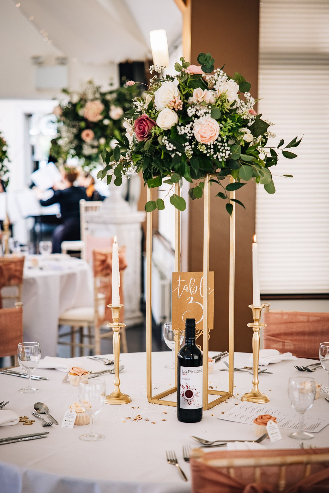 A tall floral centrepiece on a gold stand above a reception table