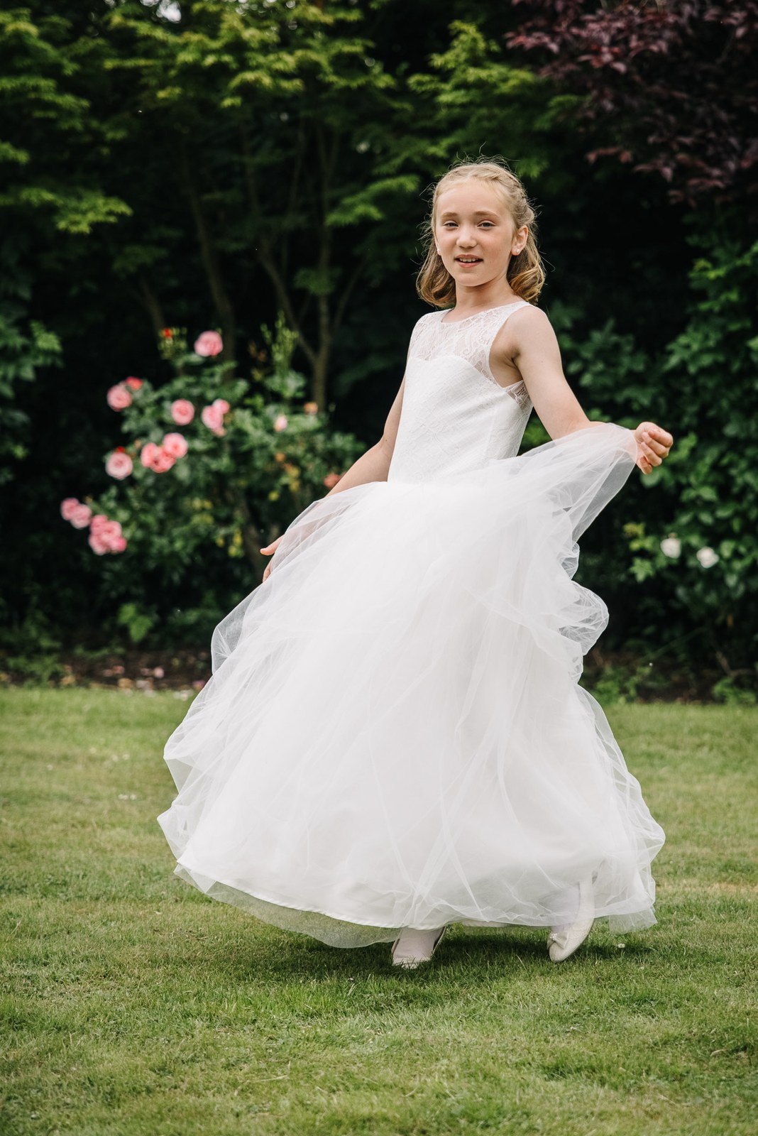 A flower girl twirling her dress on the garden lawn