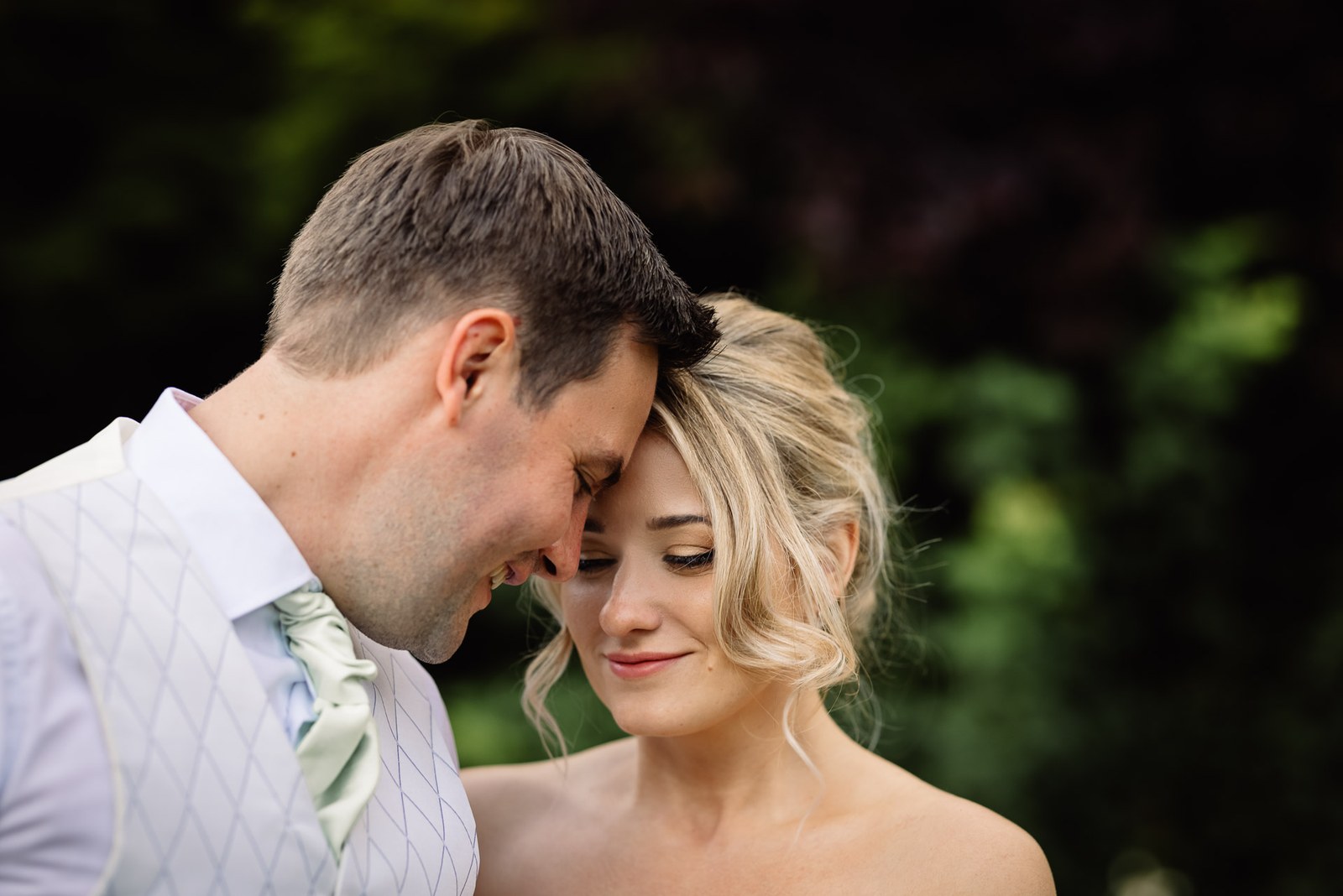 The couple resting their foreheads together in a quiet garden moment