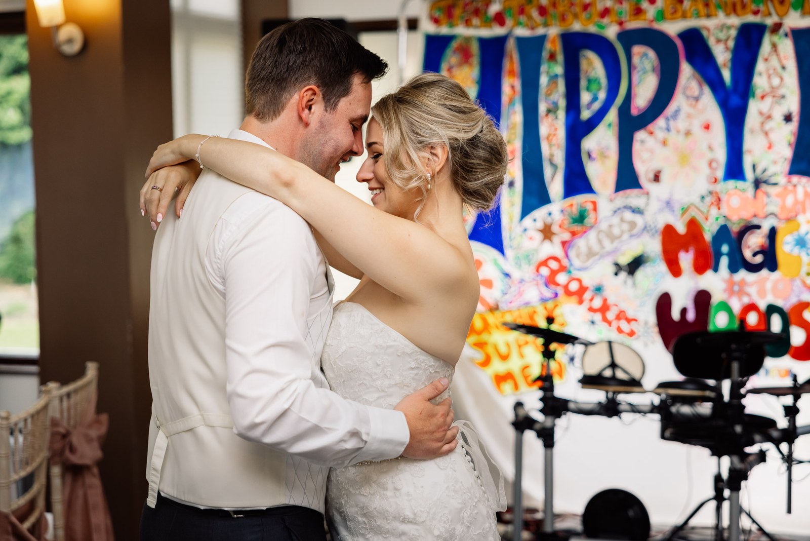 The couple embracing on the dance floor in front of the band's backdrop