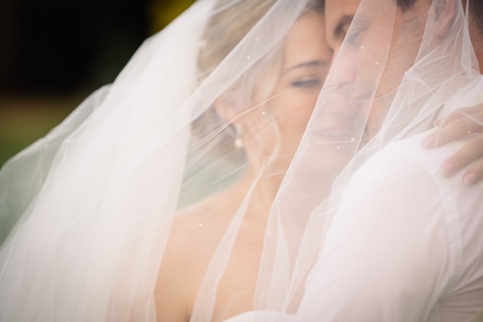 An intimate portrait of the couple's faces close together beneath the veil