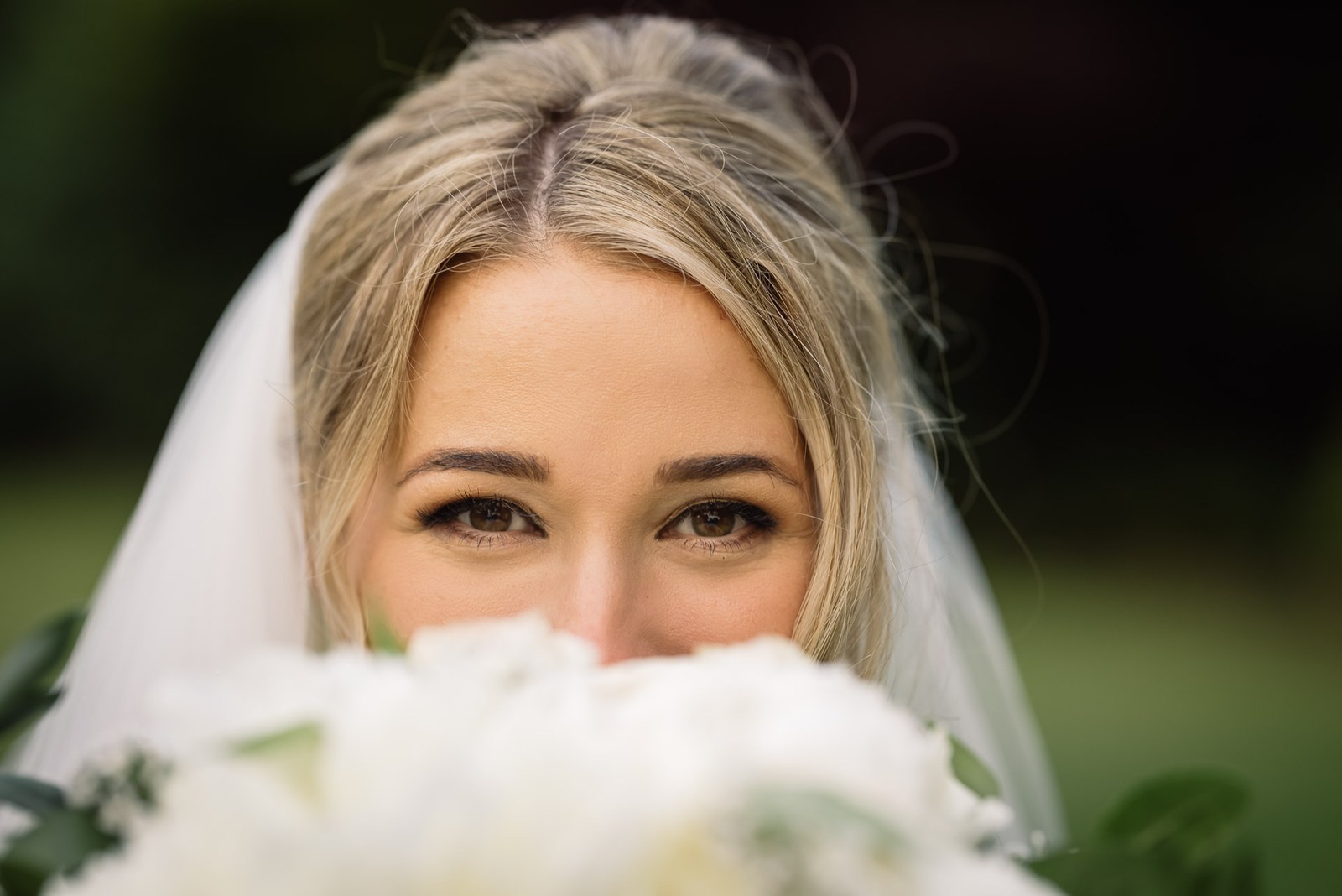 The bride's eyes above her bouquet, veil framing her face