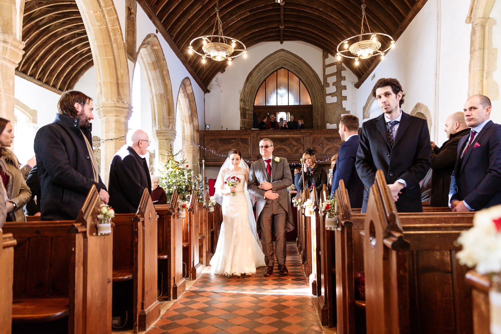 Bride on her father's arm walks the aisle of the village church
