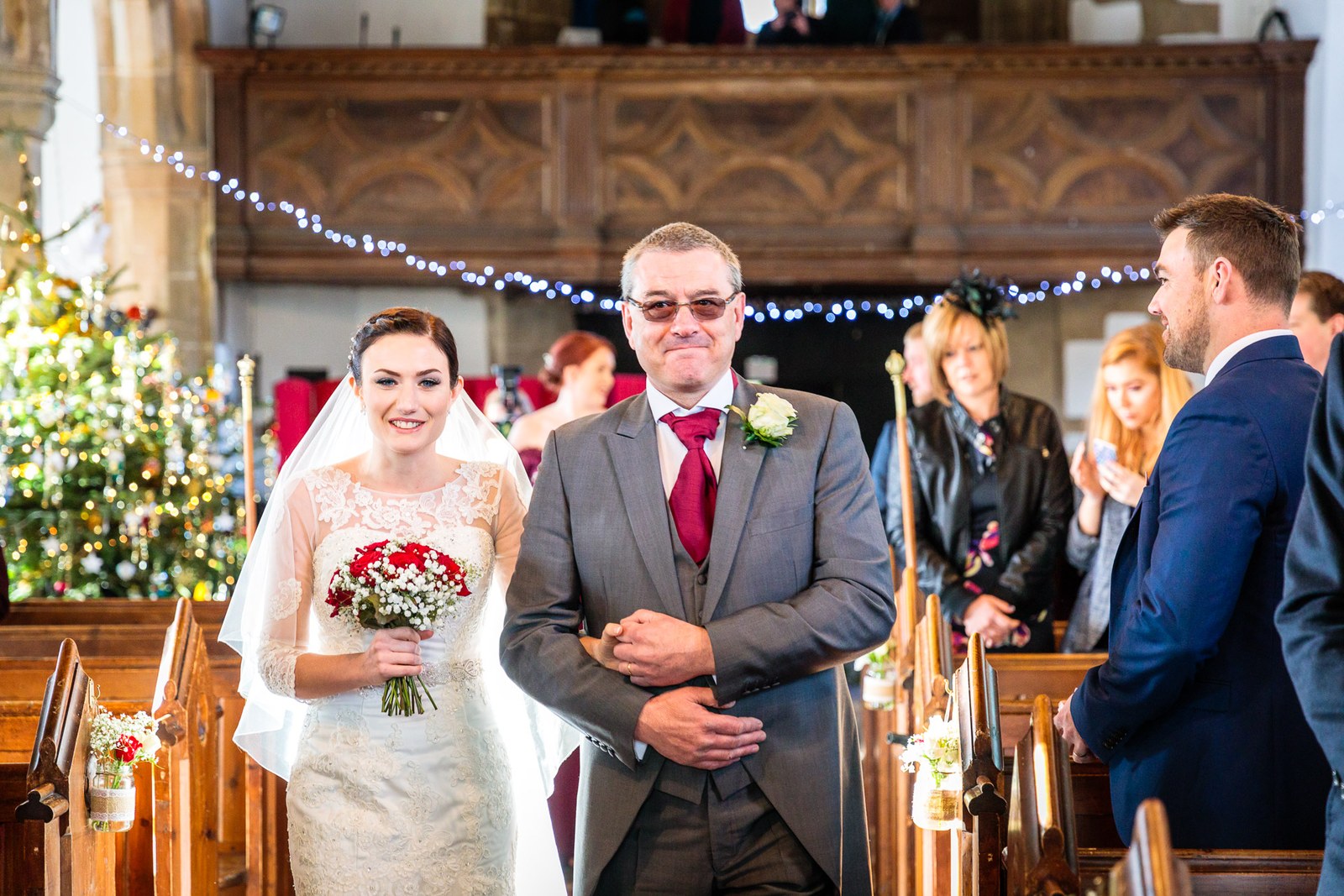 Bride and her father enter the church past a fairy-lit carved wood gallery