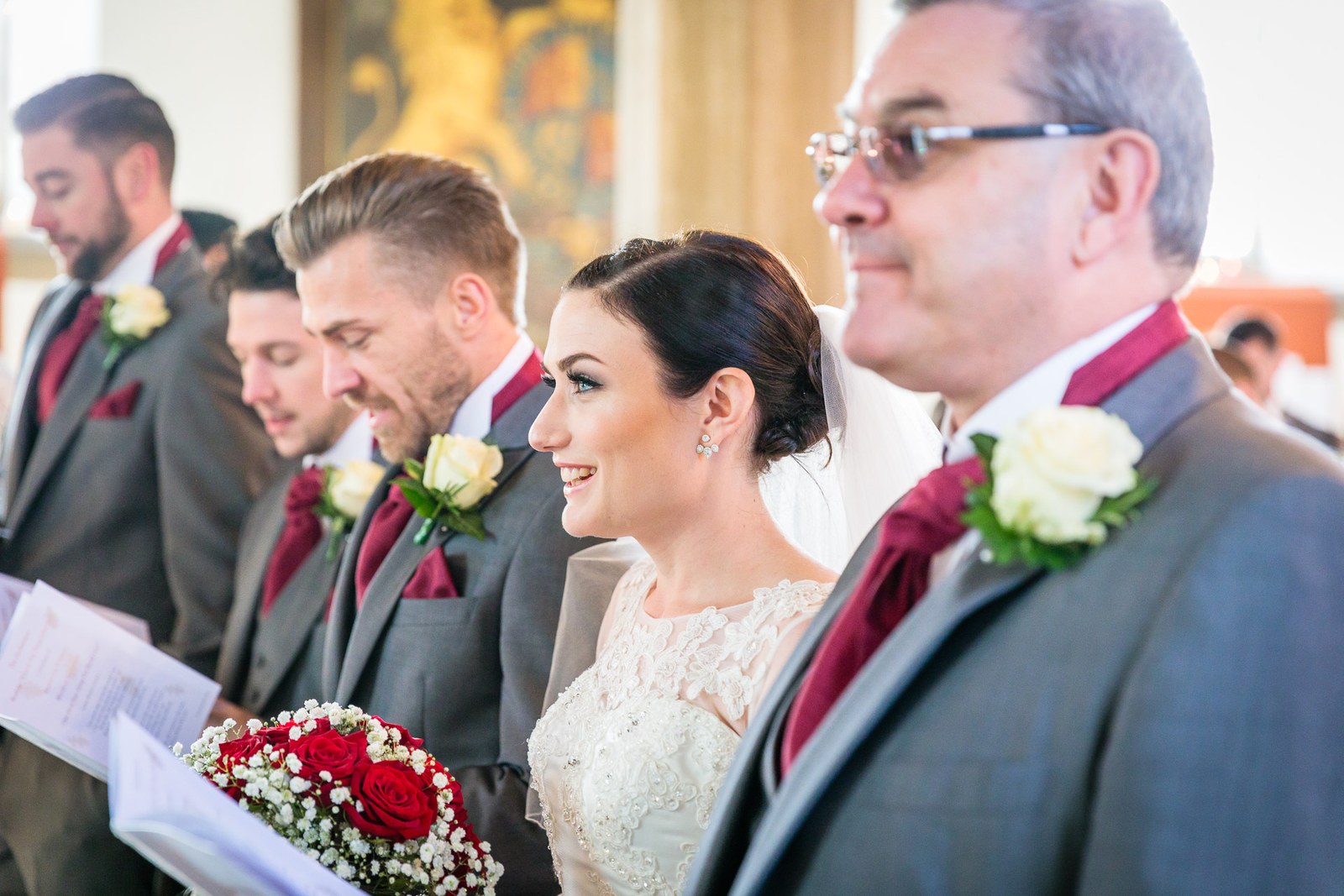 Bride with her father at the front, red rose bouquet in hand
