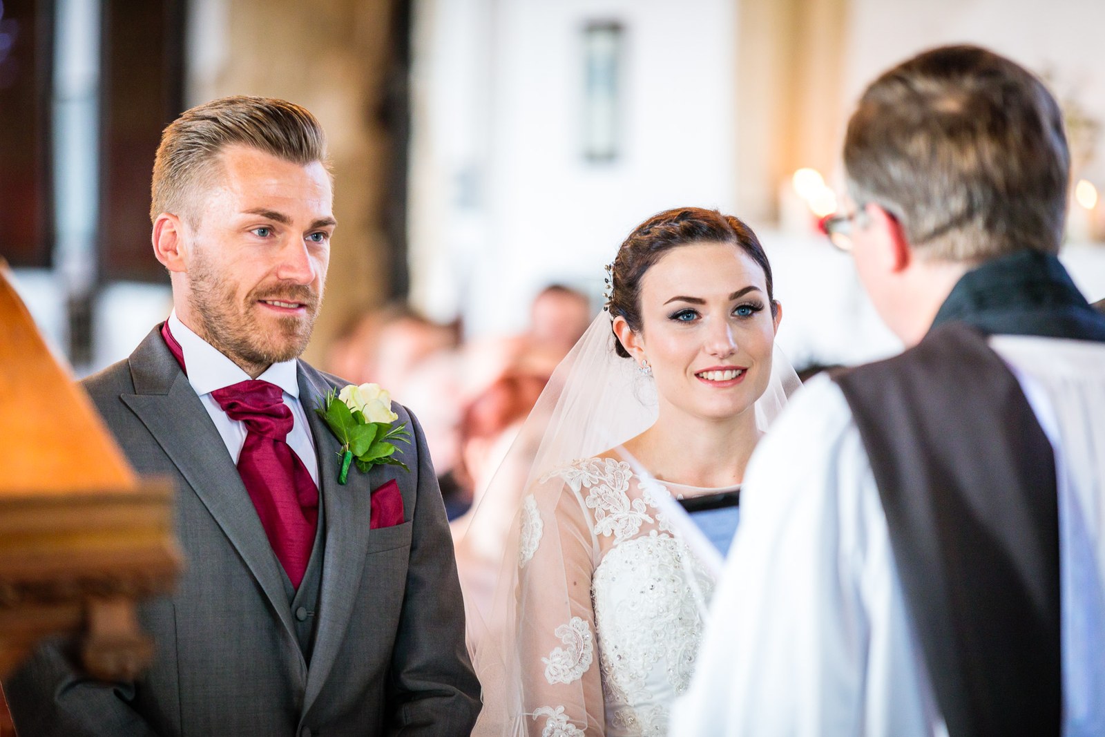 Bride and groom stand before the vicar during the church ceremony