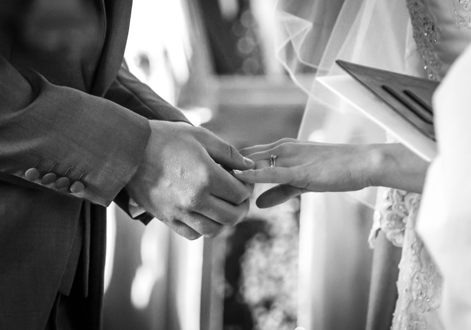 Black and white close-up of the ring being slipped onto the bride's finger