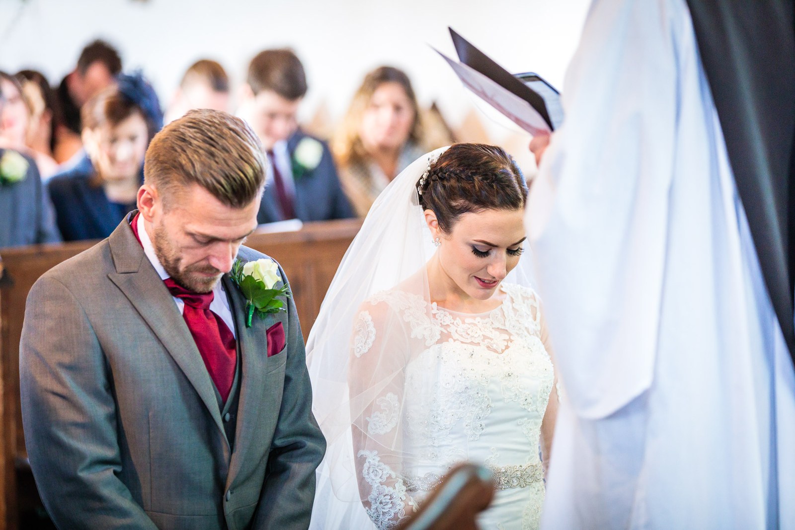 Bride and groom bow their heads as the vicar reads during the ceremony
